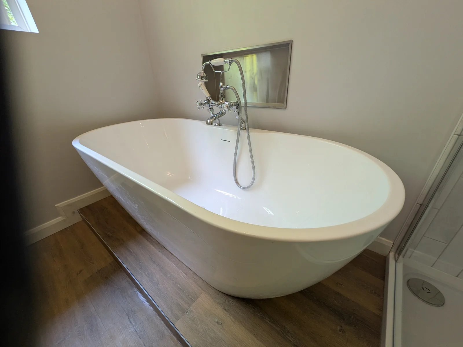A bright bathroom with a white freestanding bath and exposed traditional taps