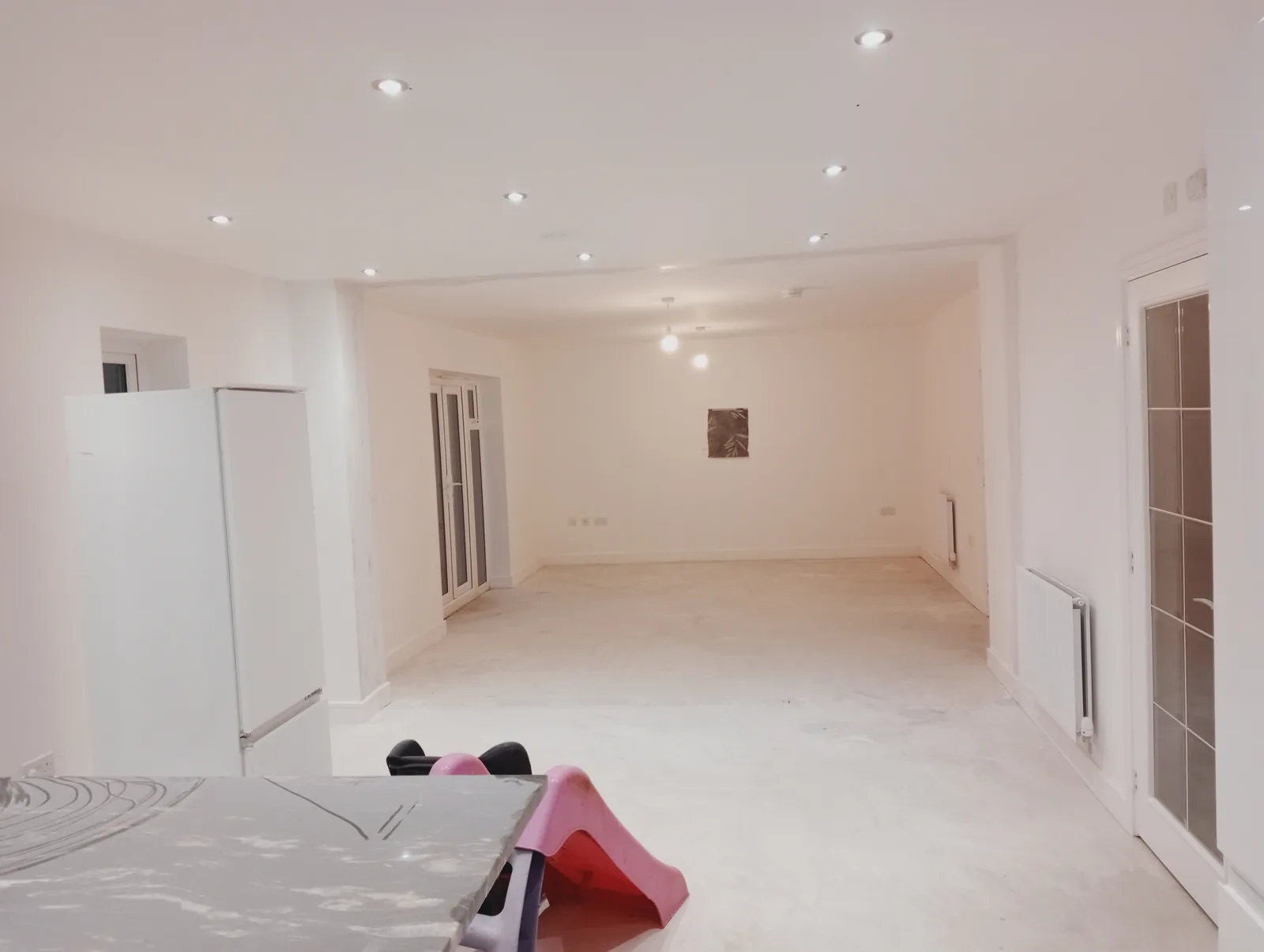 A bright, freshly plastered open-plan conversion with white walls and downlights